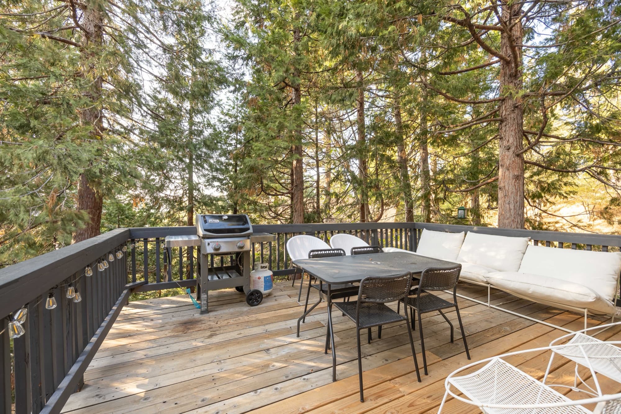 Outdoor dining on upper deck surrounded by towering pines with mountain views